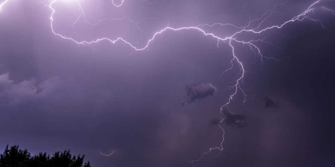 A powerful lightning strike in a bright purple sky