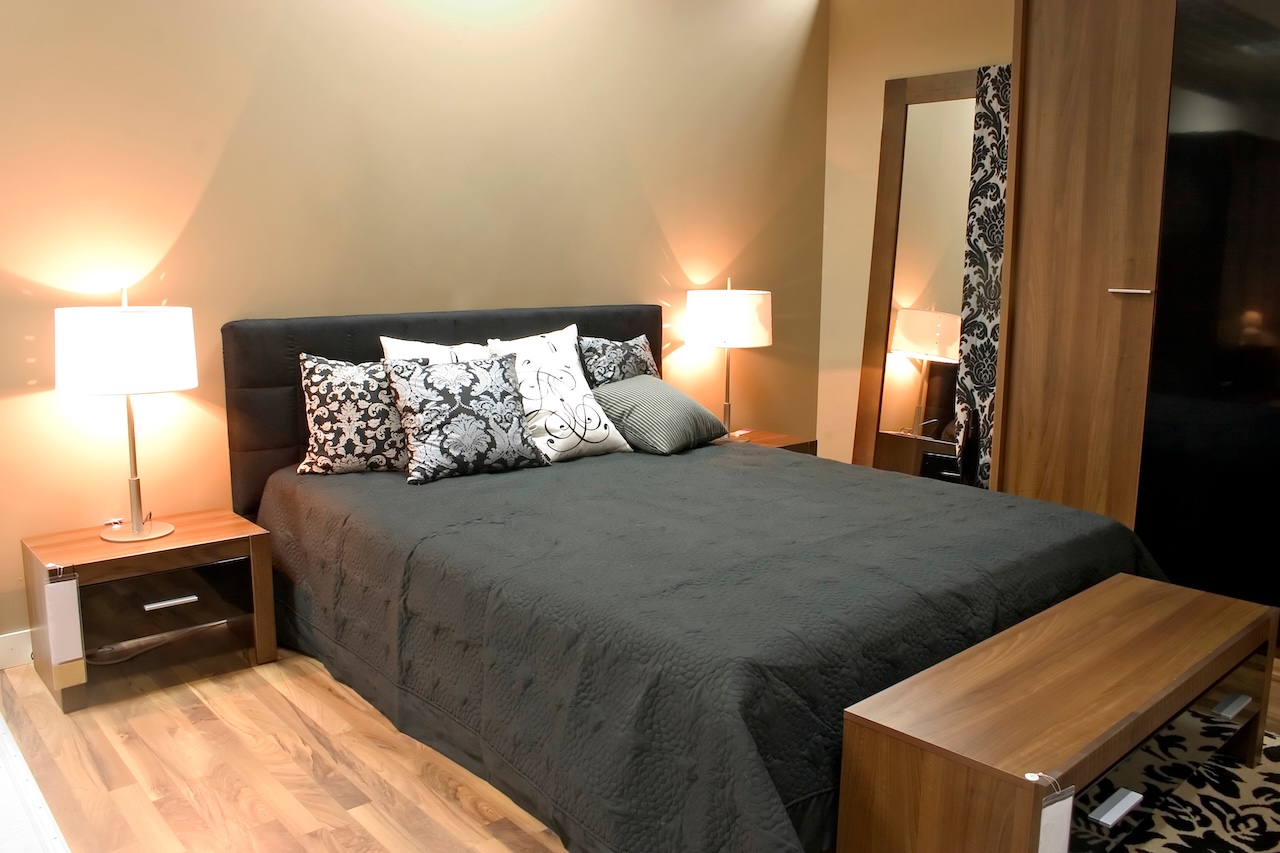 Interior of modern bedroom with furniture and mirrors in warm orange colors.